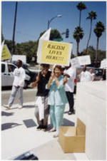 Evelyn G. Lowery poses for a photo with an unidentified man while holding protest signs outside of the Creative Artists Agency in Beverly Hills, California.
