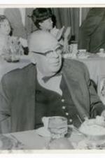 View of man wearing glasses, seated at a dining table.