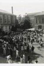 Aerial view of a crowd gathered on the lawn between buildings on campus.