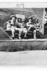 Two unidentified women sit with cowboy statues at the Ghost Town Gold Trail Hotel at Knott's Berry Farm.