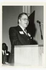 View of man at a podium. Written on verso: "Dr. Sidney Estes (unknown speaker) during Founders Week 1983".