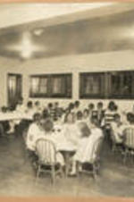 Young girls sit and eat in the dining room.