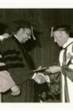 President Hugh Gloster with Louis Stokes and an unidentified person on stage. Written on verso: Congressman Louis Stokes receives Honorary Doctorate, Founder's Day, February, 1981.