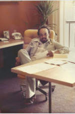 Portrait of Oscar Lewis Harris, Jr. seated behind his desk.