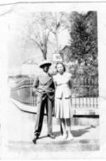 An unidentified couple stand on the corner with a sign reading "Welch" [West Virginia].