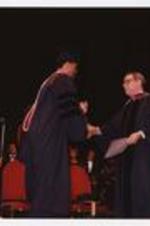 Colin Powell shakes hands with Thomas W. Cole, Jr. on stage at the summer commencement.