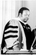 C. Eric Lincoln receives his honorary hood in a ceremony at Saint Michael's College with Dr. Reddick and President Senghor standing nearby.