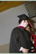 An unidentified faculty member has an exchange with a graduate as he crosses the stage.