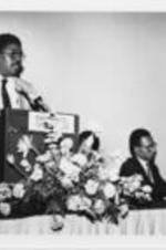Ron Jenkins is shown speaking at the 1st National Conference on AIDS and the Black Community while Dr. Huey Mays, Dr. Lawrence Sanders, and Elfreda Stanley listen. For more details on the conference, see pages 42-45 of the August-September 1986 SCLC Magazine: http://hdl.handle.net/20.500.12322/auc.199:07030. Written on verso: Ron Jenkins, Dr. Huey Mays, Dr. Lawrence Sanders, Elfreda Stanley.