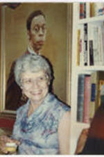 L. Alexander stands in front of a portrait of Dr. Richard Long. Written on verso: L. Alexander at [the] home of Dr. Richard Long (Spring, 1981 or �82). Portrait of Dr. Long in background. Mrs. Lillian Lewis on right. Taken by (and gifts of) Ms. Susan Ross.