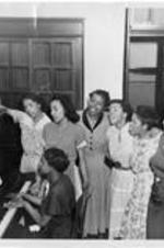 Women gathered by piano one plays the others sing. Written on verso: Students in Women's Dept. Gammon 1949-1950, Left to right: Ruby L. Taylor, Louise Hamm, Sara McGhee, Iola T. Risher, Evelyn Smith, and Lillie B. Roberts seated at piano Dorothy L. Barnette.