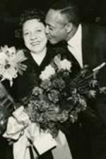 Virginia Lacy Jones receiving an award with flowers and a kiss.