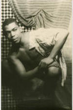 Portrait of Alvin Ailey crouching on a pedestal. Written on verso: Alvin Ailey; Photograph by Carl Van Vechten; 146 Central Park West; Cannot be reproduced without permission; March 22, 1955.
