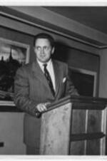 Edward B. Alford stands at a podium. Written on verso: Edward B. Alford at A.U. April 2, 1944