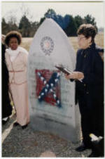Evelyn G. Lowery speaks next to the Viola Liuzzo memorial monument, which is vandalized with the painting of a Confederate flag. Dr. Gwendolyn M. Patton stands at left in the photo.