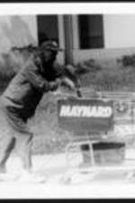 A man pushes a grocery cart with a Maynard Jackson sign.