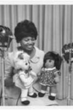 An unidentified woman plays with puppets on a sound stage.