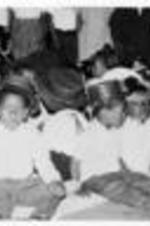 Unidentified children sit wearing hats. Written on recto: Above: Children at play. Bottom picture with children dressed for May Day performance.
