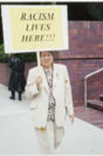 Evelyn G. Lowery holds a protest sign that reads "Racism Lives Here" as she pickets outside the William Morris Agency office in Beverly Hills, California.