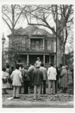 A group gathers outside of a house.