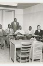 Indoor view of men seated at desks.