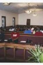 A congregation sitting in chapel pews. Written on verso: Vacation Bible School - 2007. Rev. E.W. Hooks, Greg Lewis Sr., Aaron Christian, Rose Wavei, Linda Campbell.