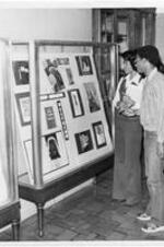 Two students look at an exhibit in a display case.
