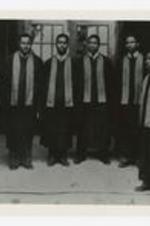 A group portrait of men wearing graduation gowns.