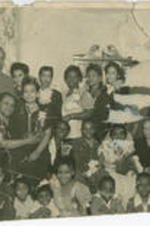 Men, women, and children stand and sit together for a picture at a wedding. An unidentified woman sits in Elizabeth McDuffie's lap (middle row, left) while Irvin McDuffie can be seen on the far right.