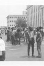 Two men speak in front of a horse drawn carriage during the March Against Repression. Written on accompanying document: Scenes of the March in Progress.