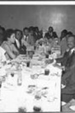 A group gathers at a large table for a banquet inside the ITC dining hall.