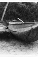 Damaged row boats parked in a group on the beach. The front ends are cracked and eroding.