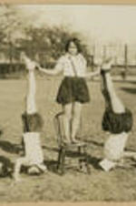 Girls wear exercise outfits and perform headstands and balance formations.