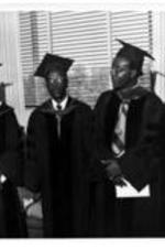 Left to Right: James P. Brawley, Robert E. Penn, and an unidentified man and woman wear commencement caps &amp; gowns.