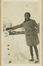 A girl stands with a snowman.