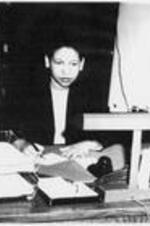 Gladys Barbara Taylor, Secretary to Dean McPheeters, sits behind a desk.