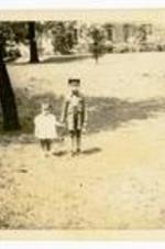 Gladstone "Mickey" Chandler, Jr. standing with unidentified child in the grass. Written on verso: Morehouse campus.