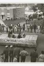 Street view of women seated on a convertible parade float "Miss Omega".