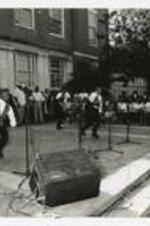 A group of young men dance in front of a building at a homecoming activity.